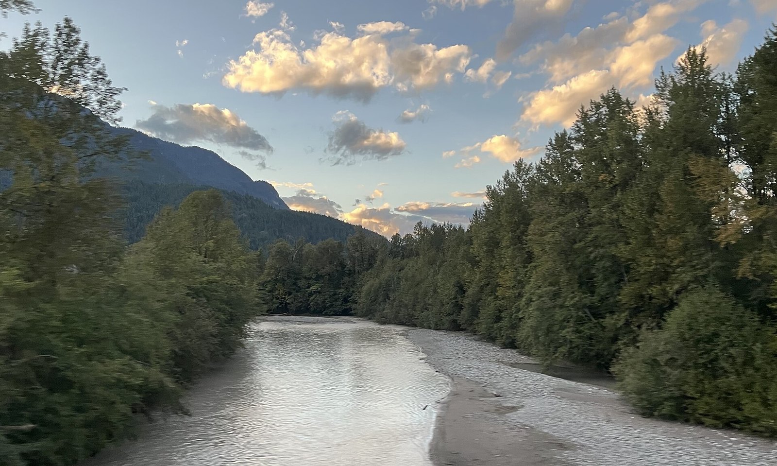 Glacial river with gravel bar between forested banks at dusk