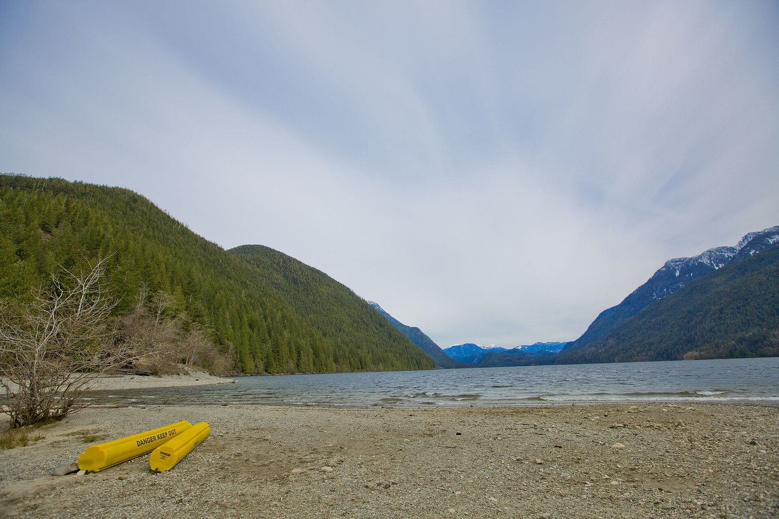 Pebble beach on Alouette Lake with yellow booms and mountains