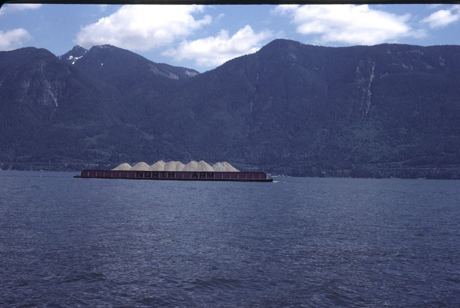 Gravel barge on Howe Sound below forested mountains