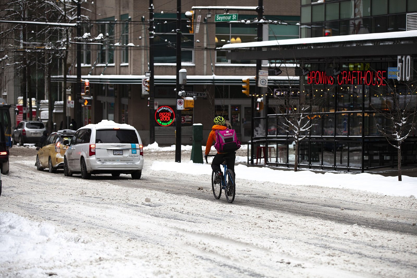A food courier cycles through the snow on Seymour Street at Pender, downtown Vancouver, January 15, 2020